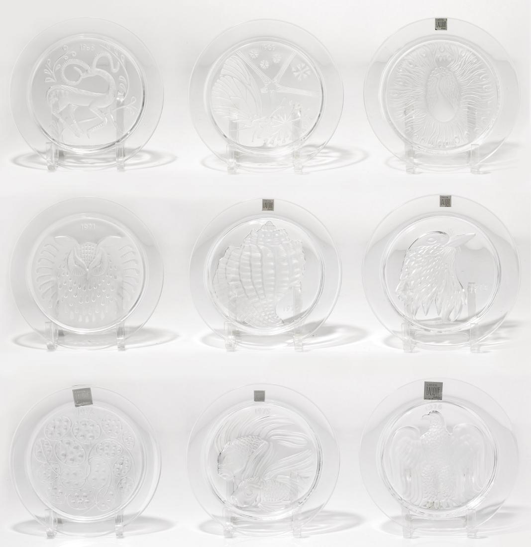 A suite of Lalique glass annual plates, 1968-76: A suite of Lalique clear and frosted glass annual plates dating from 1968-76 Each etched Lalique France, some with adhesive factory labels. diameters ranging from 8 1/4 to 8 1/2in (21 to 21.5cm)