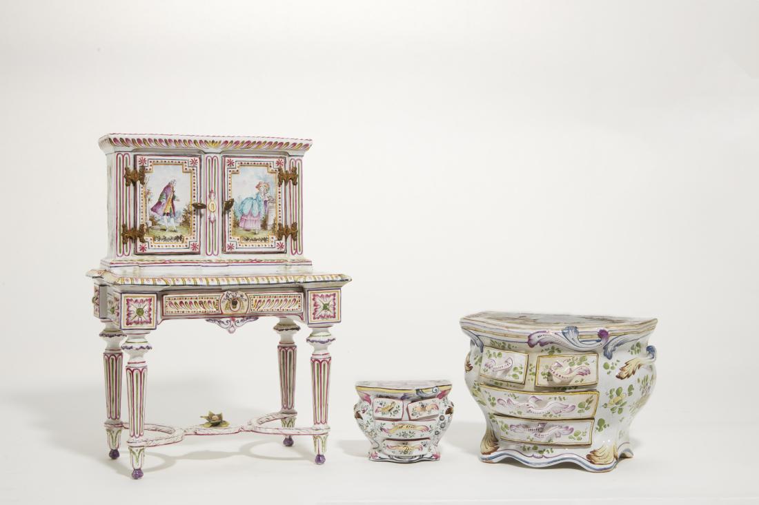Three French faience minature furniture pieces: Three French faience articles in the form of miniature furniture 20th century Comprising a ladies' writing desk and two bombe commodes; the desk with red painted fleur de lys mark, the large commode w