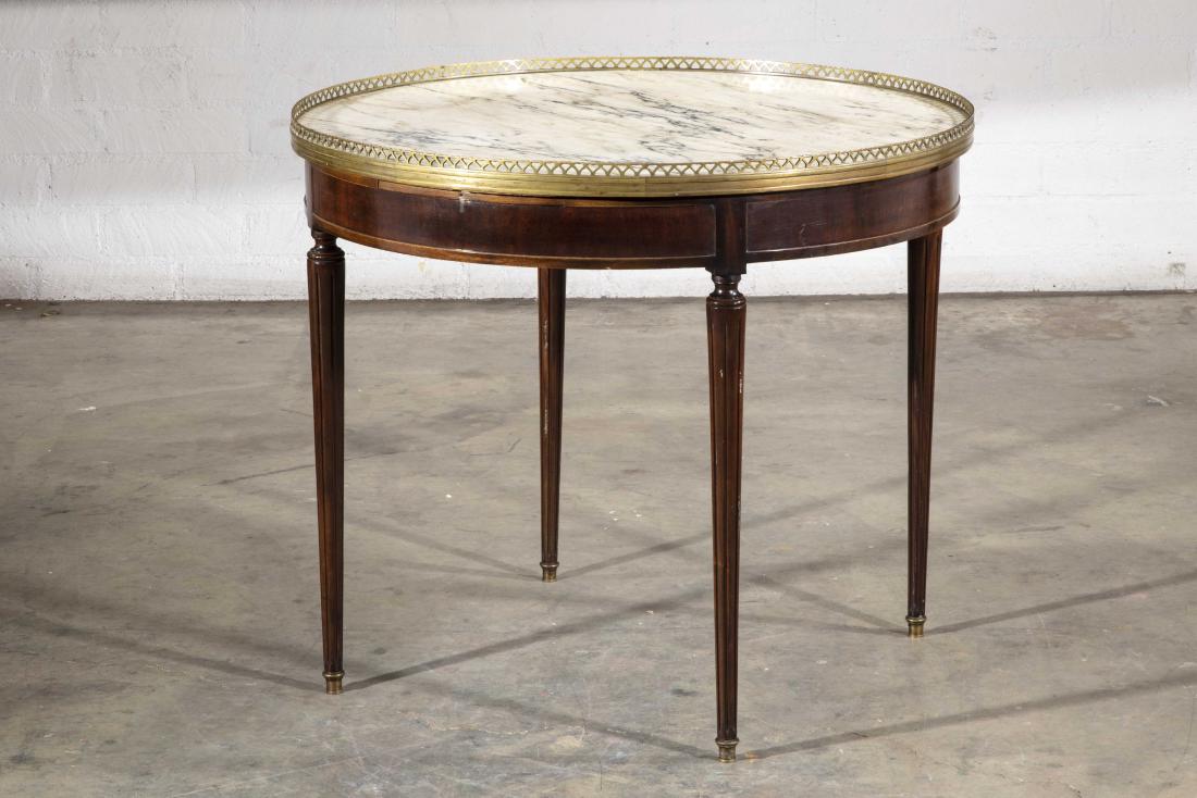 A Louis XVI style mahogany bouillotte table: A Louis XVI style brass mounted mahogany bouillotte table first half 20th century Inset with a marble top, fitted with two slides to the frieze. height 28 3/4in (73cm); diameter 33 1/4in (84cm)