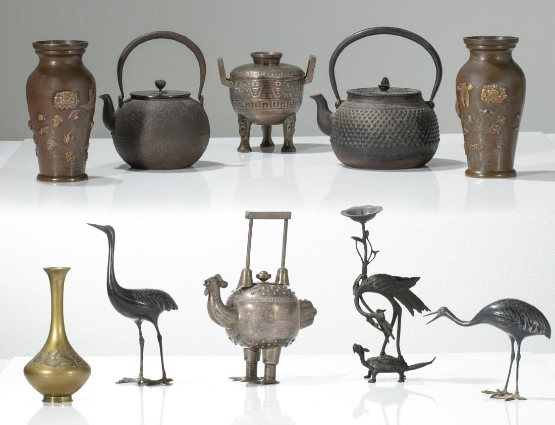 A group of ten Asian metalware table decorations: A group of ten Asian metalware table decorations mostly Japanese, 20th century Comprising a pair of vases, two tea kettles, a chicken form teapot, a footed lidded bowl, a bottle vase, a pair of models