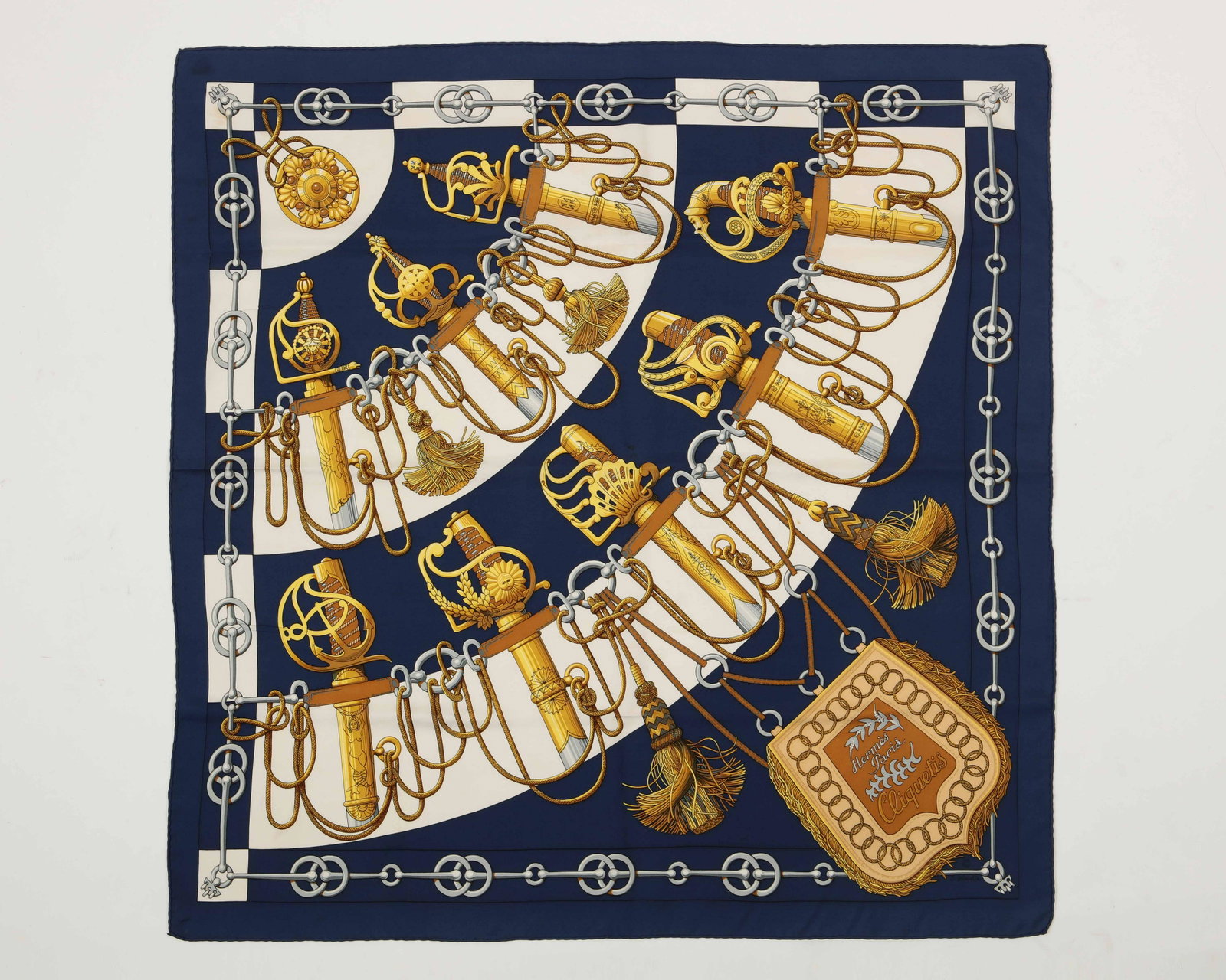 A Hermes Paris silk scarf, J. Abadie: A Hermes Paris silk scarf Signed J. Abadie, blue grround with beige semi circles and horse bit gray border and gold and silver sword tops and Christian tassels hanging along with a medallion purse on 