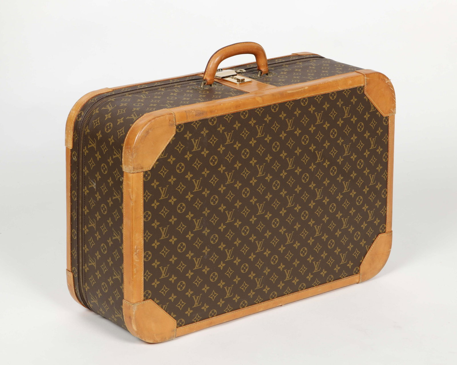 A Louis Vuitton monogram Stratos hard suitcase: A Louis Vuitton monogram Stratos hard-side suitcase 1980s Brown and tan coated canvas with a rolled leather top handle and zipper closure. height 18 1/4in (46cm); width 27 1/2in (70cm); depth 9in (23c
