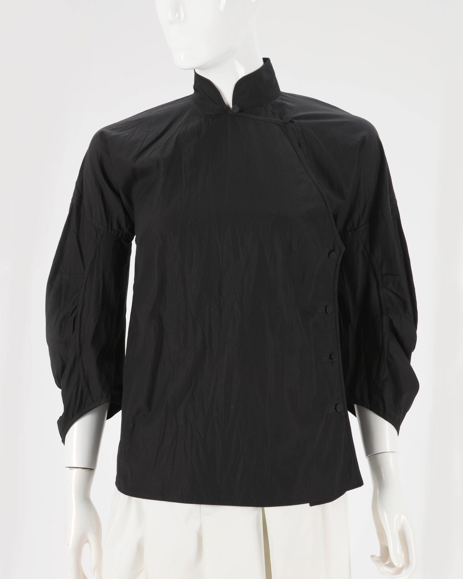 A Prada black blouse and a Prada skort: A Prada black mandarin collar blouse, size 38, together with a Prada cream pleated skort, no size label 1990s Cotton blouse ruched with side buttons and pin tux detail in back. Skirt with wide waist b