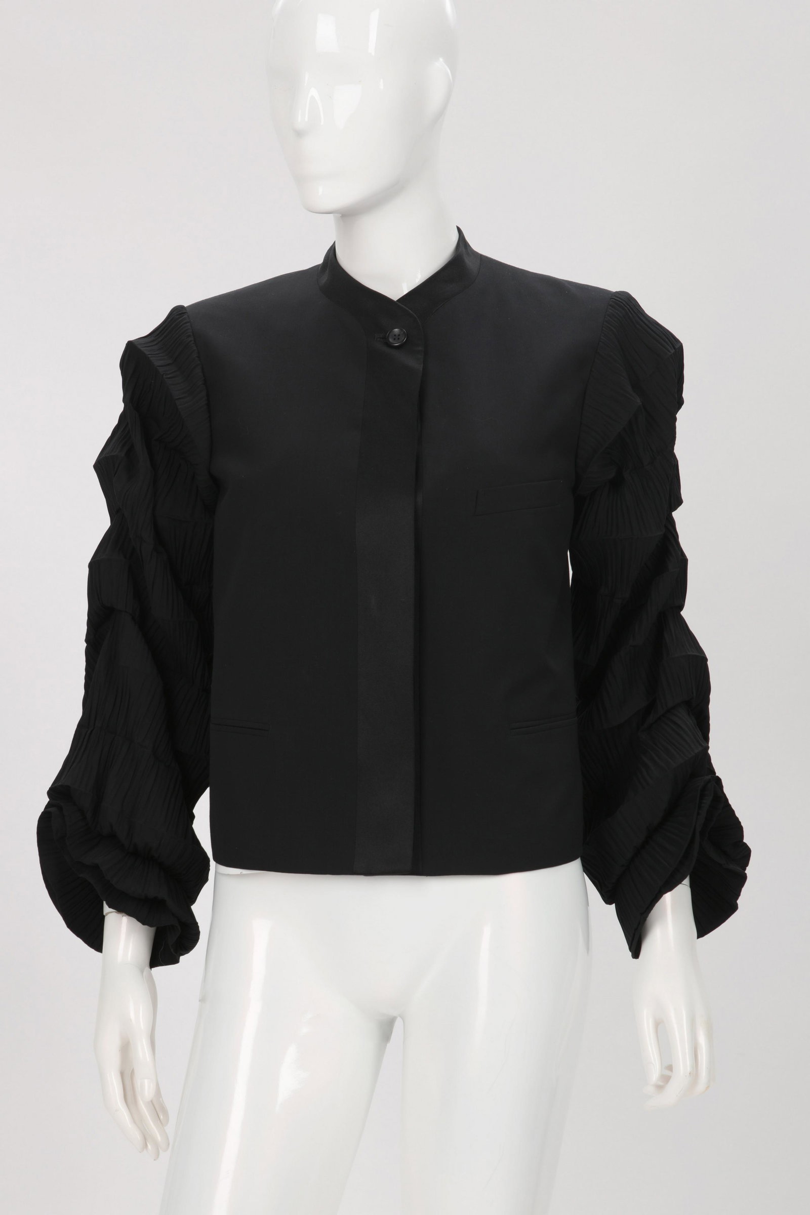 An Issey Miyake black evening jacket, size small: An Issey Miyake black evening jacket, size small 2000s This wool long sleve jacket with satin trim to collar and hem with satin button front closure. Sleeves with accordion pleats and closed horizonta
