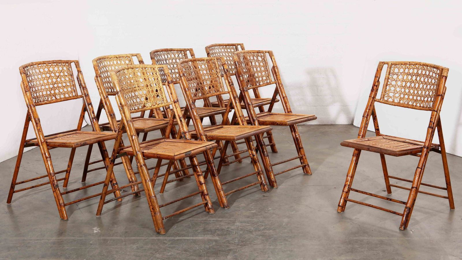 A set of eight bamboo and rattan folding chairs: A set of eight bamboo and rattan folding chairs height 34 1/2in (87.5cm); width 18in (45.75cm); depth 15in (38cm) Provenance: Property from a Private Beverly Hills Collection, curated by Hendrix Allar