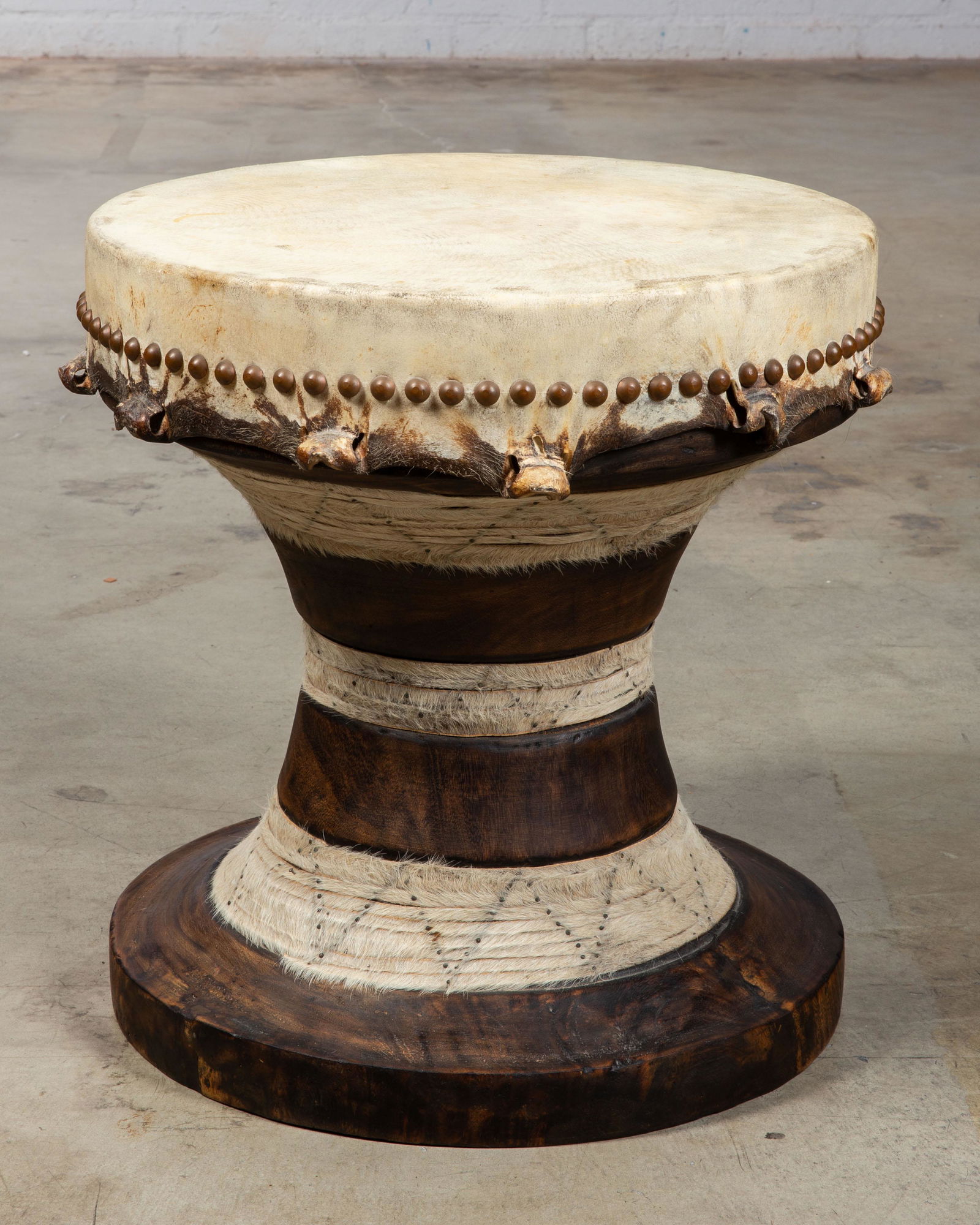 African turned hardwood, hide and nailhead drum: An African turned hardwood, hide and nailhead drum 20th century height 20 1/2in (52cm); diameter 19 1/2in (49.5cm) Provenance: With JF Chen, Los Angeles, California.