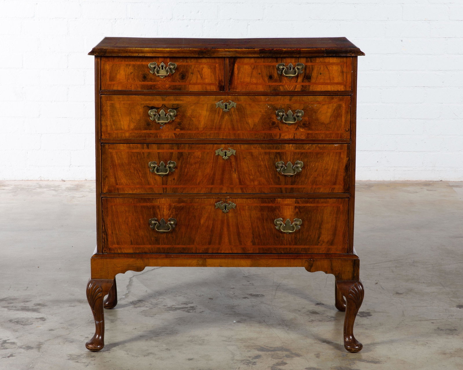 A George II style walnut chest on stand: A George II style crossbanded walnut chest on stand incorporating antique and later elements height 43in (109cm); width 38 1/2in (98cm); depth 22 1/2in (57cm) Provenance: Property from the Estate Fran