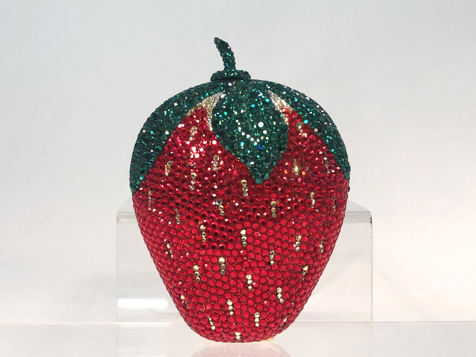 A Kathrine Baumann Strawberry minaudiere: A Kathrine Baumann limited edition Strawberry minaudiere The interior lined in metallic leather, with tuck away gold tone shoulder chain, applied factory label, numbered 2/500. height 5in (12.5cm); wi