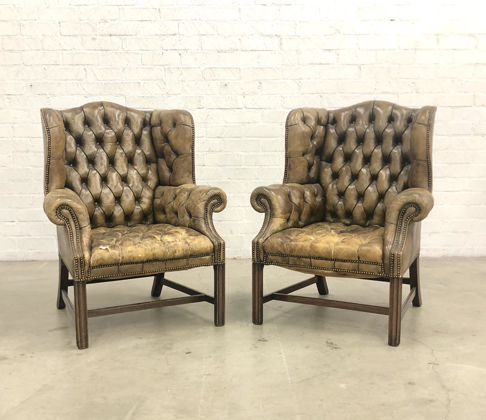 A pair of George III style wing armchairs: A pair of George III style tufted leather upholstered wing armchairs post 1950 height 43in (109.25cm); width 34in (86.5cm); depth of seat 21 1/2in (54.5cm)