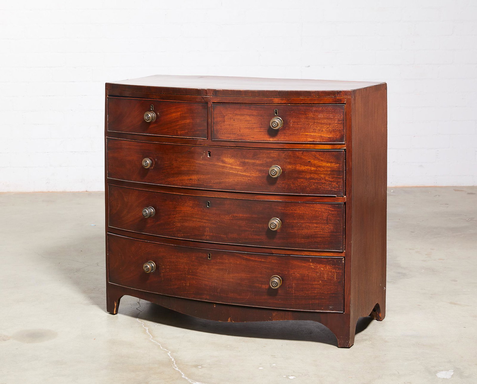 A George IV inlaid mahogany bowfront chest: A George IV inlaid mahogany bowfront chest early 19th century height 38 1/2in (98cm); width 42in (107cm); depth 21 1/2in (55cm) Provenance: Property from a Private Collector, Palm Springs.