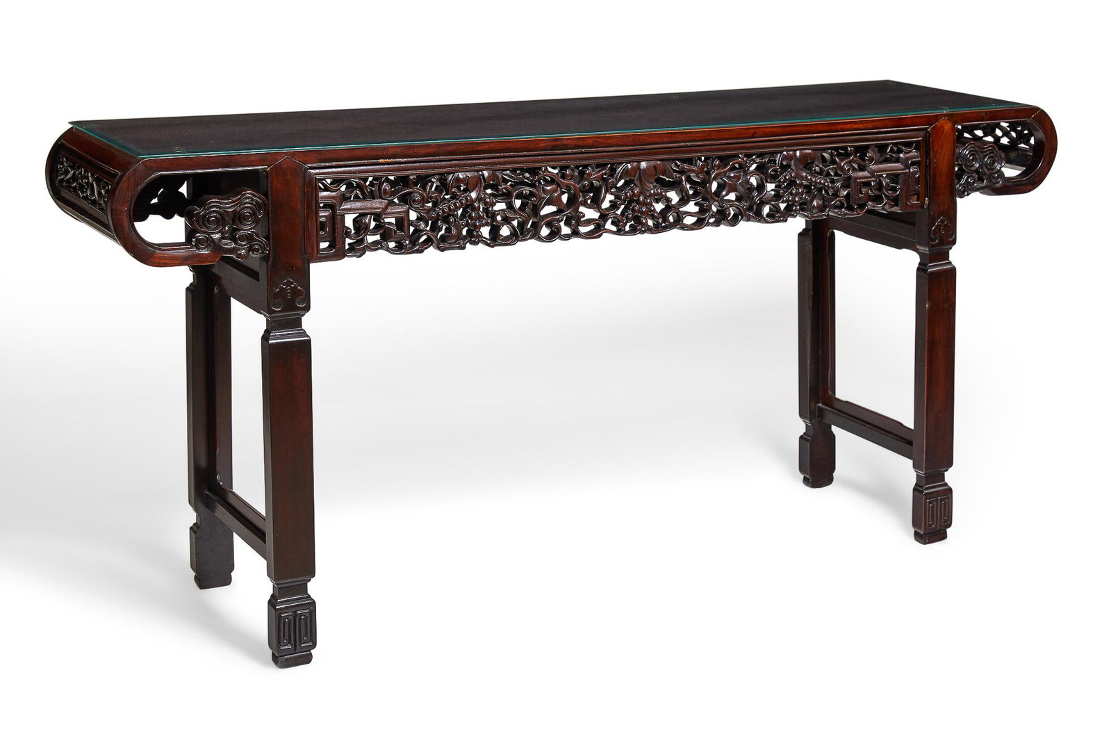 A Chinese carved hardwood console table: A Chinese carved hardwood console table 20th century Surmounted by a glass top with beveled edge. height 33 1/2in (85cm); width 72in (183cm); depth 16 3/4in (42.5cm) Property from the Estate of June E