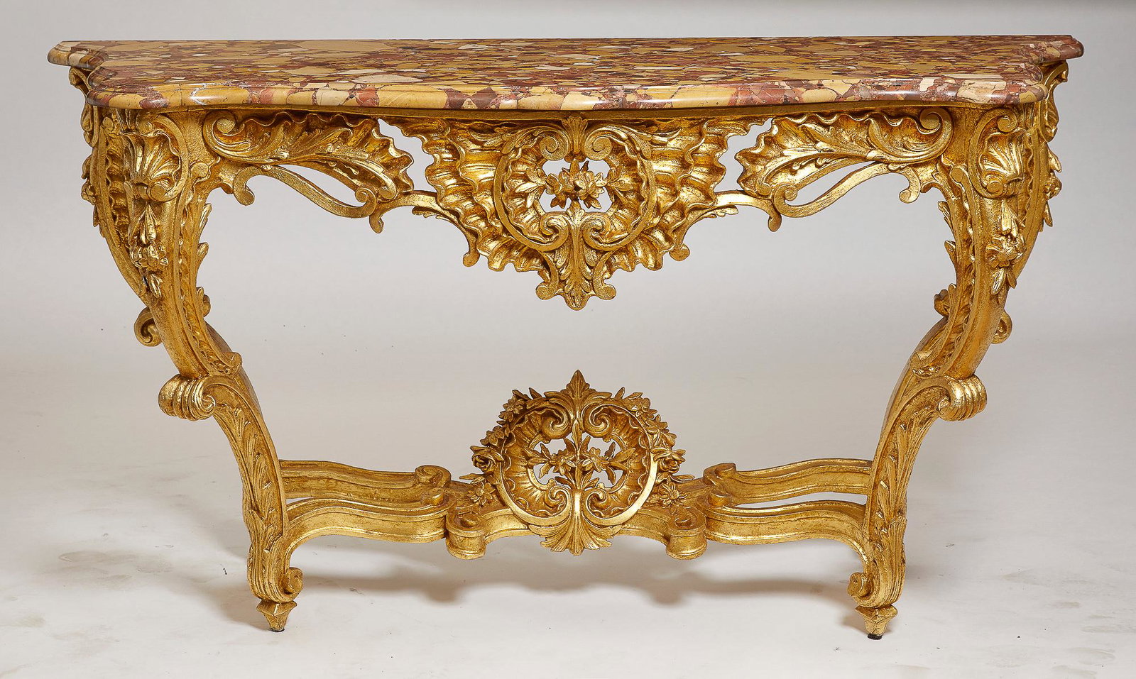 A Louis XV style carved giltwood console: A Louis XV style carved giltwood console late 19th century Surmounted by a marble top. height 36 1/2in (92.5cm); width 67in (170.5cm); depth 26in (66cm) Provenance: Property from the Estate of June Eb
