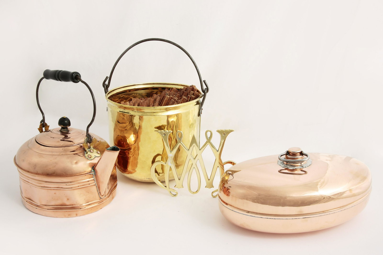 Four brass & copper wares Revere and other makers: Four brass and copper wares Revere and other makers 20th century Comprising a kettle, a bed warmer a trivet and a kindling bin. the kindling bin height 8in (20cm); width 11in (28cm); depth 10in (25.5c