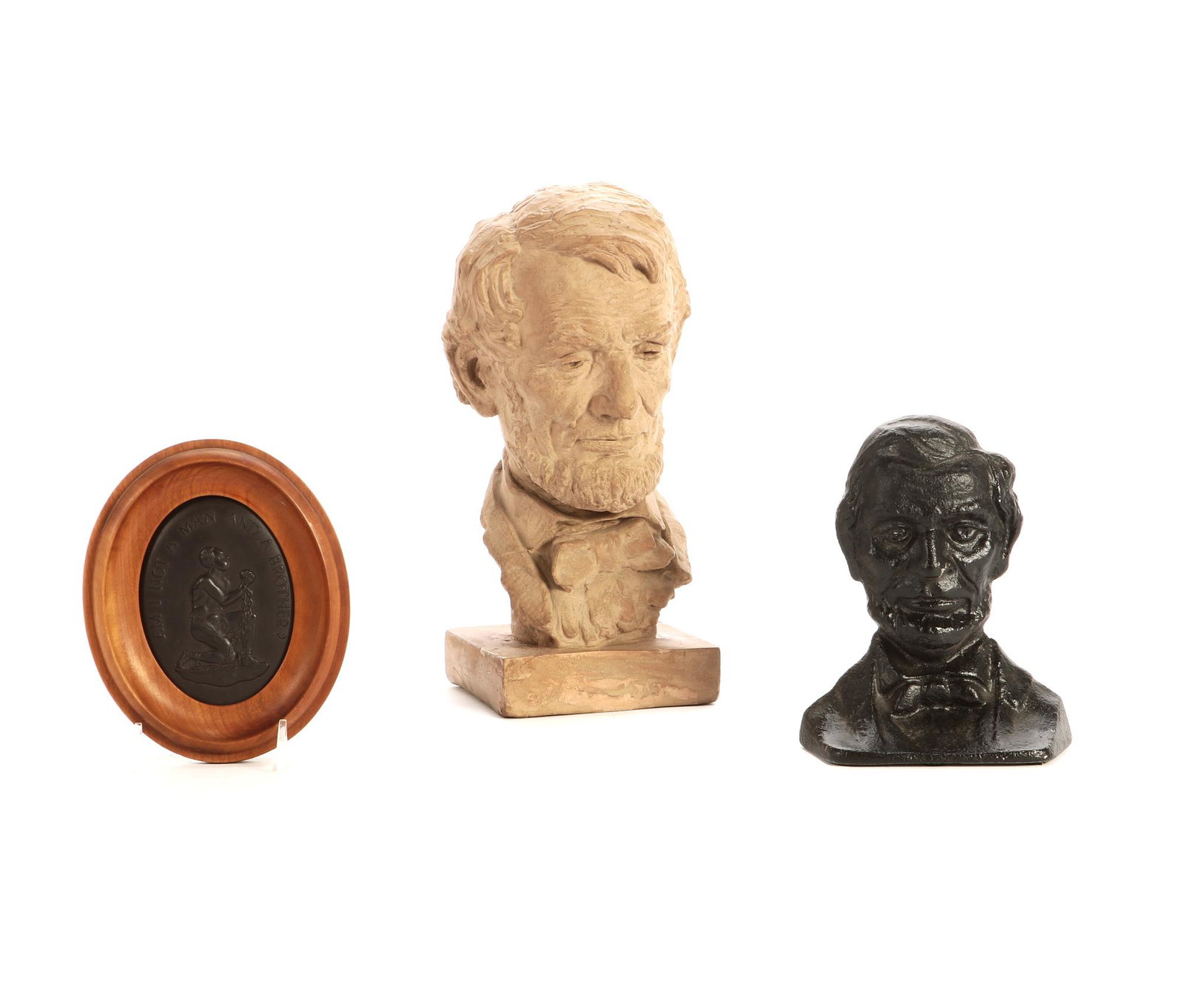 A pottery bust of Abraham Lincoln: A tinted pottery bust of President Abraham Lincoln 20th century Together with a Wedgwood black basalt plaque: "AM I NOT A MAN AND A BROTHER?" and a black painted cast iron door stop of Presi