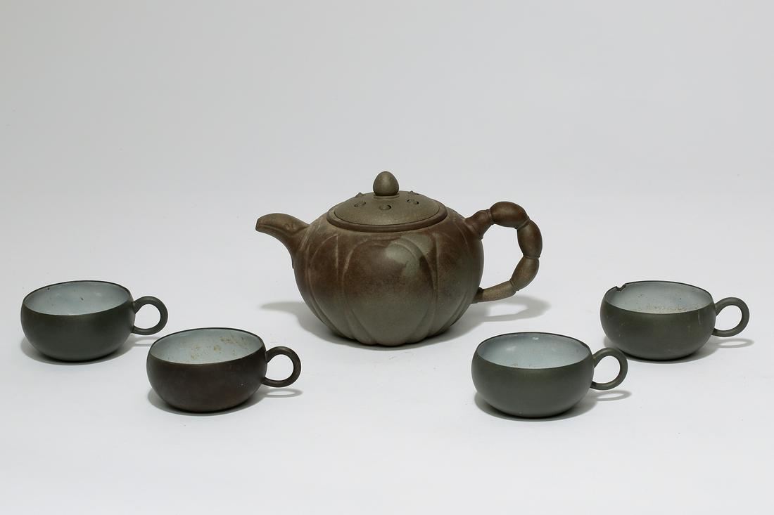 AFive piece Chinese grey yixing pottery tea set: An assembled five piece Chinese grey yixing pottery tea setComprising a teapot and four semi glazed cups, teapot with impressed mark to underside of top, cups with impressed marks to undersides.the te