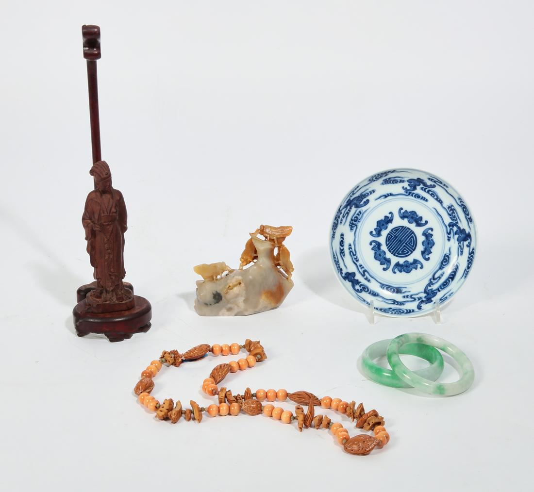 Seven Asian table articles and jewelry: A collection of seven Asian table articles and jewelryComprising a carved wood figure, a soapstone carving, a blue and white porcelain dish two jadeite bangles, a strand of stained wood and nut shell