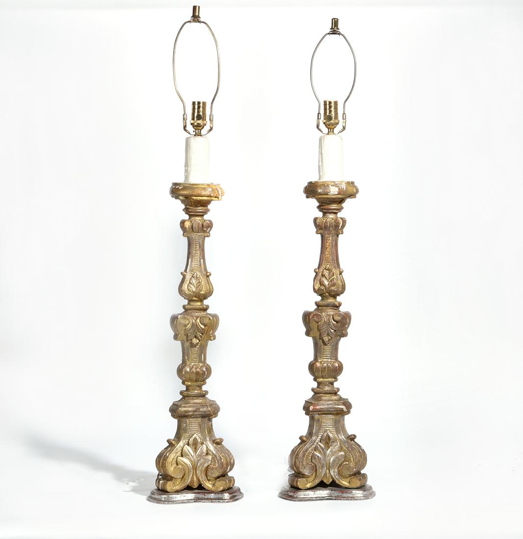 A pair of Baroque style prickets as table lamps: A pair of Continental Baroque style parcel silvered carved giltwood prickets as table lamps 20th century height excluding electrical fittings 32in (81cm); height to top of finial 43in (109cm)