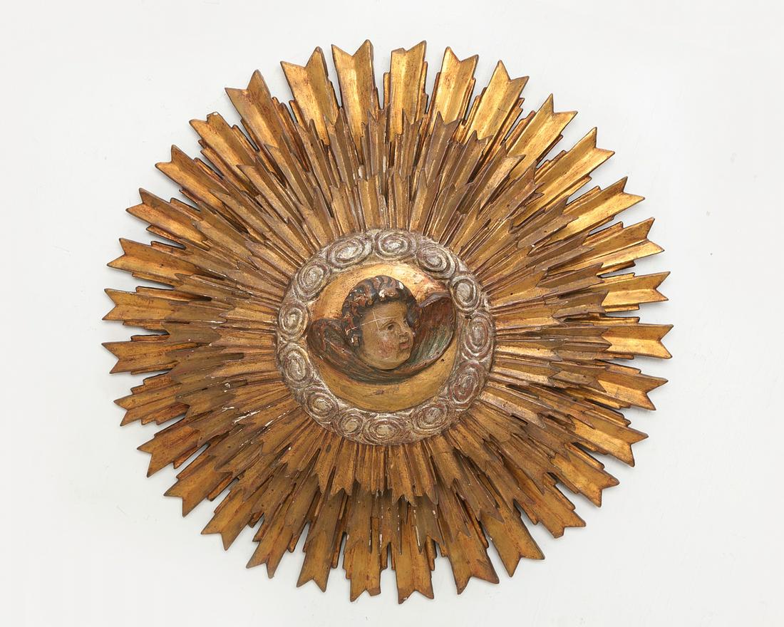 A Baroque style sunburst wall mount: A Continental Baroque style giltwood and polychrome decorated sunburst wall mount diameter 22in (56cm); depth 9 1/2in (24cm) Provenance: Property from the Collection of Raymond Enkeboll.