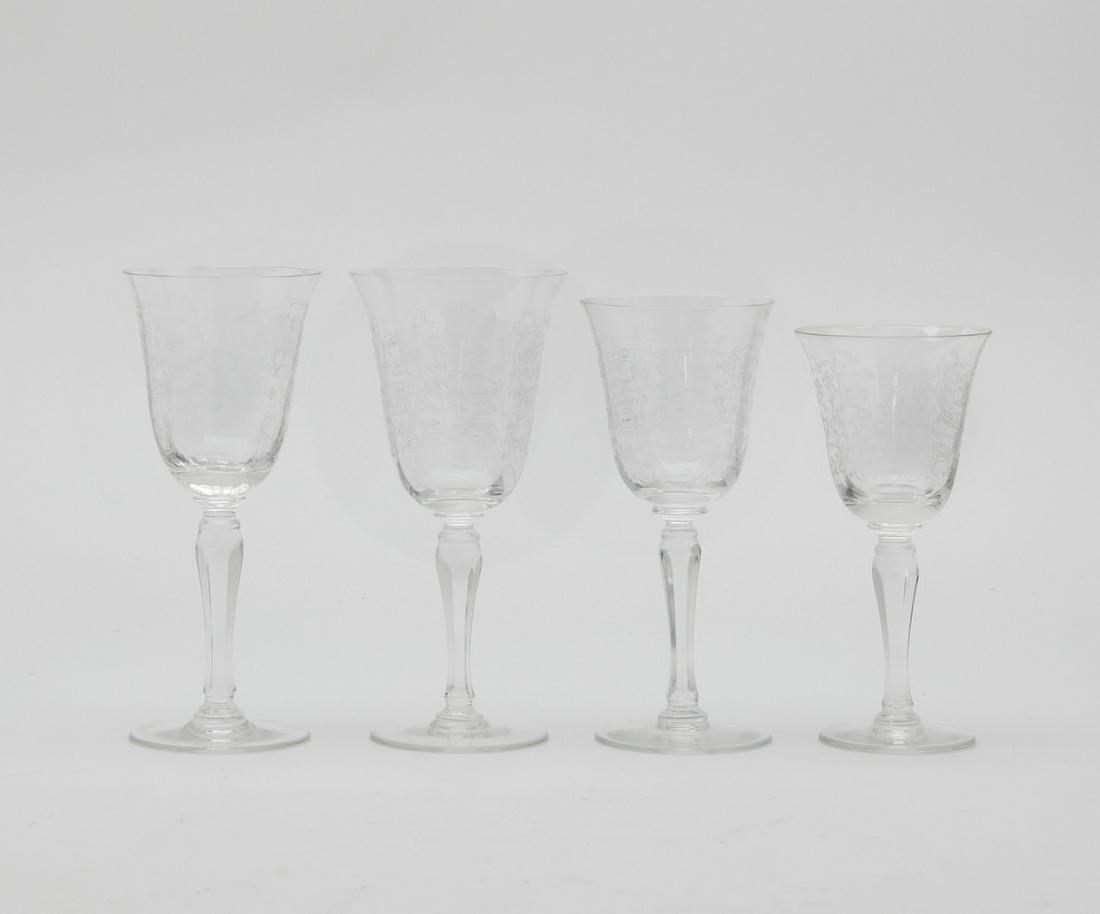 A suite of engraved clear glass stemware: A suite of engraved clear glass stemware 20th century Comprising seven 6 3/4in red wine glasses, twelve 6 3/4in white wine glasses, twenty-two 6 3/8in glasses and eleven 6in glasses. (52)