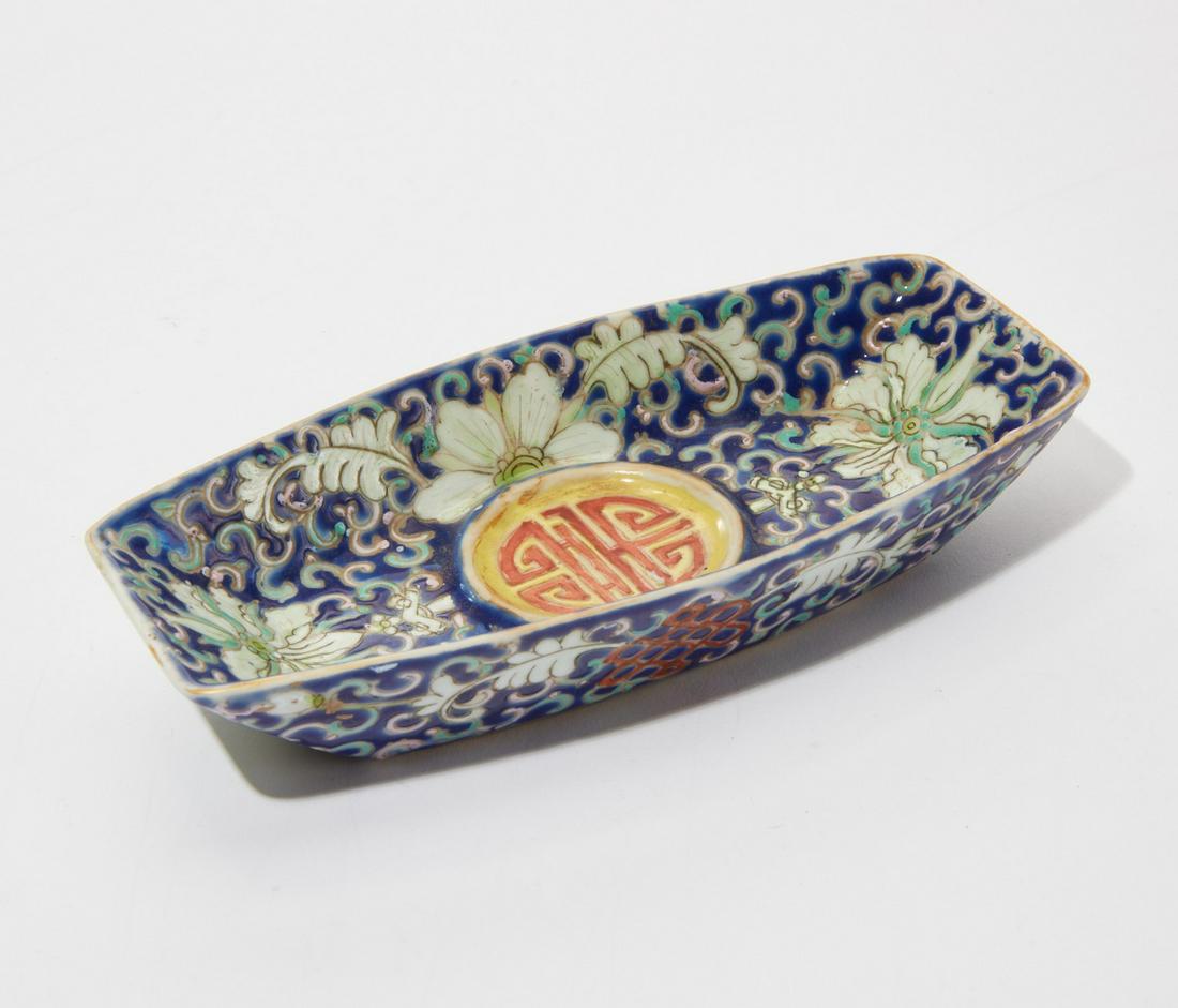 A Chinese enamel porcelain dish: A Chinese polychrome decorated enamel porcelain ovoid dishWith lotus vine decoration and a Shou medallion in the center.height 1in (2.5cm); length 6in (15cm); depth 3in (7.5cm)