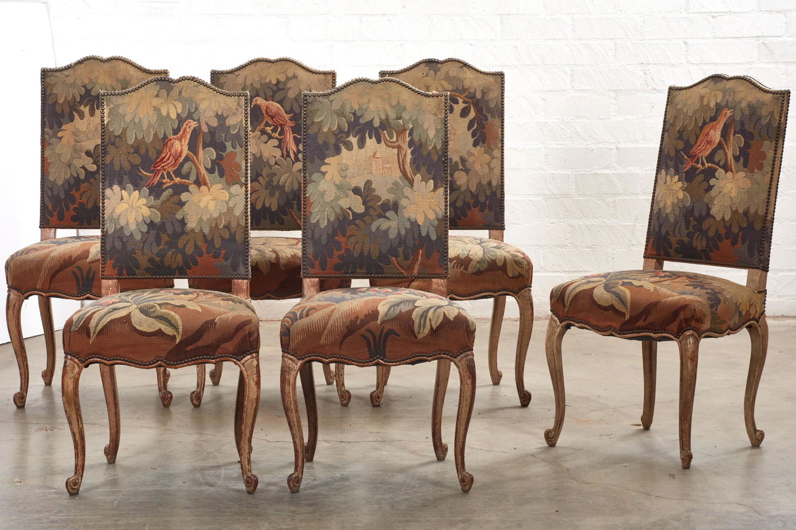 Six Louis XV style verdure tapestry chaises: A set of six Louis XV style verdure tapestry upholstered white painted chaises19th centuryheight 42in (107cm); width 20in (51cm); depth of seat 17in (43cm)
