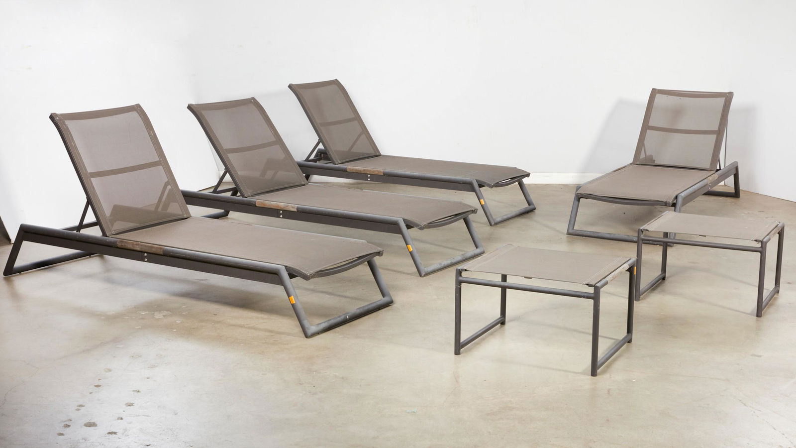 A six piece Harbour Outdoor patio lounge suite: A six piece Harbour Outdoor grey painted metal and teak patio lounge suitepost 1950Comprising four adjustable chaises longue and two ottomans/side tables with Serge Ferrari fabric.the chaises highest