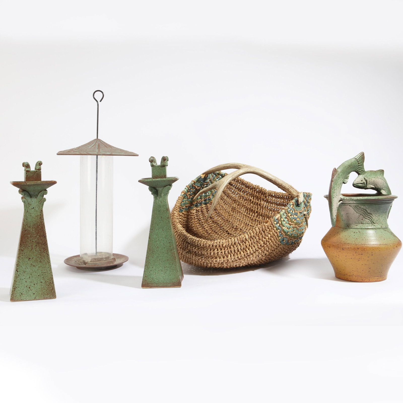 A five piece group of decorative objects: A five piece group of decorative objectsmodernComprising a pair of pottery candlesticks and vase signed ROBINSON, a woven basket with antler handle and a copper painted metal bird feeder.the vase heig