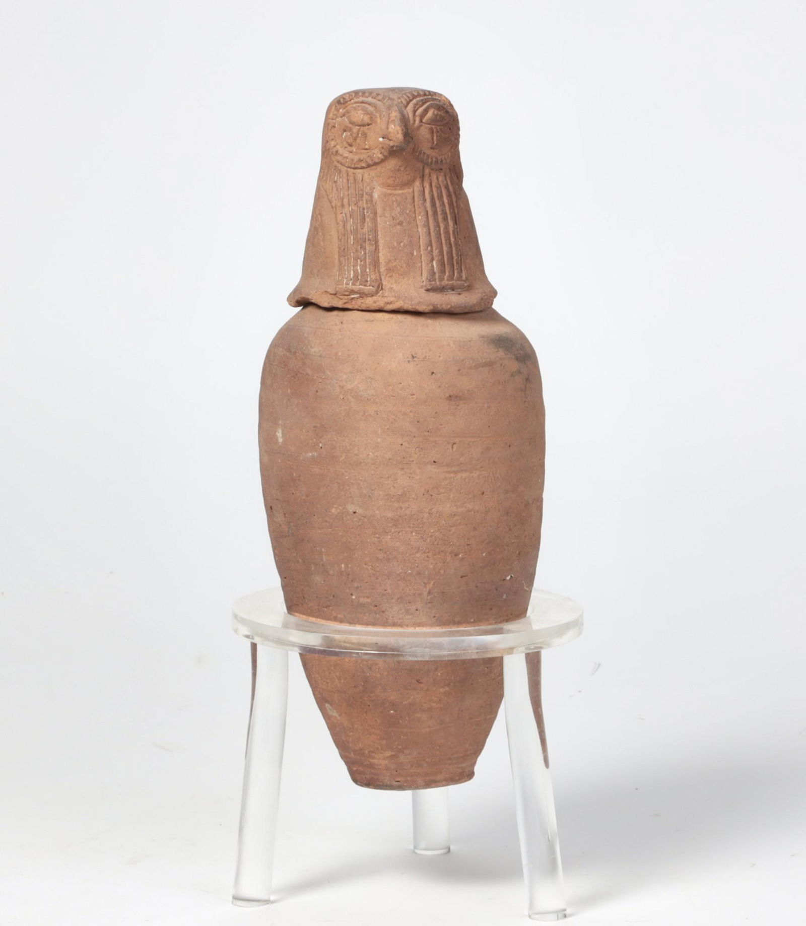 An earthenware canopic jar: An earthenware canopic jar19th century possibly earlierOn display stand.height 13in (33cm); width 5 1/2in (14cm) overall height 15 1/2in (39cm)