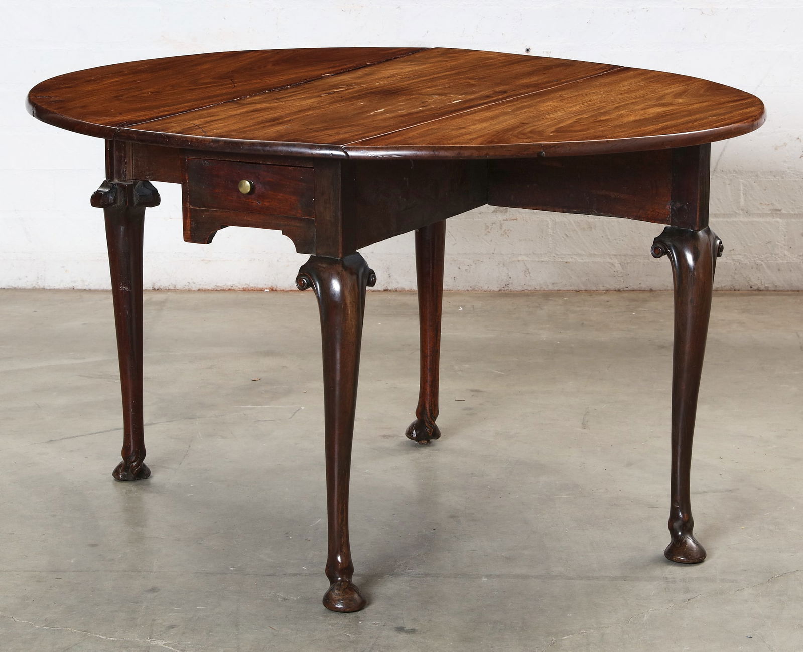 A George II walnut drop leaf table: A George II walnut drop leaf tablemid-18th centuryFitted with a single drawer to one end.height 28 3/4in (73cm); width 49 1/4in (125cm); depth 42in (106.5cm) Provenance:Property of a Northwest Family