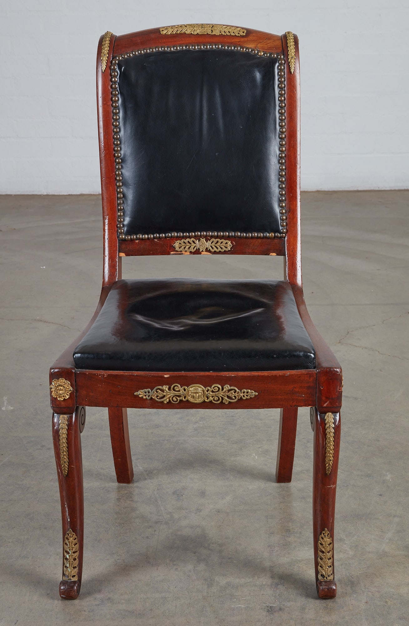 An Empire style gilt bronze mounted mahogany chaise: An Empire style gilt bronze mounted mahogany chaise late 19th century height 34in (86.5cm); width 17 1/2in (44.5cm); depth of seat 14 1/2in (37cm)