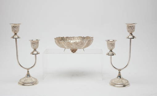 An assembled three piece Persian silver garniture: An assembled three piece Persian silver table garniture 20th century Comprising a pair of two light candleabra and a footed bowl. the candelabra height 12 1/2in (32cm); width 6 1/4in (16cm); depth 4