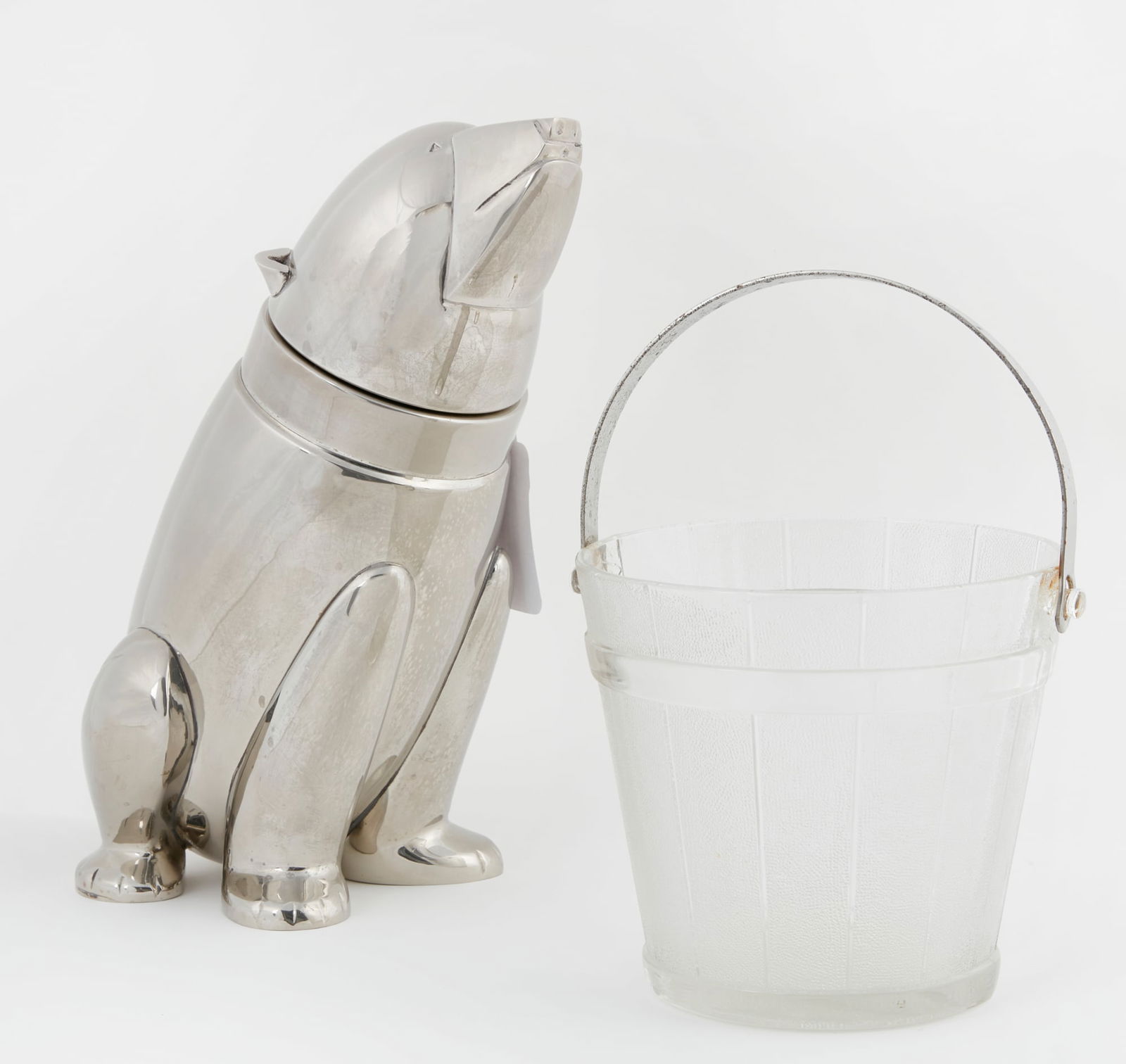 A silverplate cocktail shaker: A silverplate cocktail shaker modeled as a polar bear20th centurytogether with an etched glass ice bucket. (2)height 10in (25.5cm); width 5 1/2in (14cm); depth 7 1/2in (19cm)
