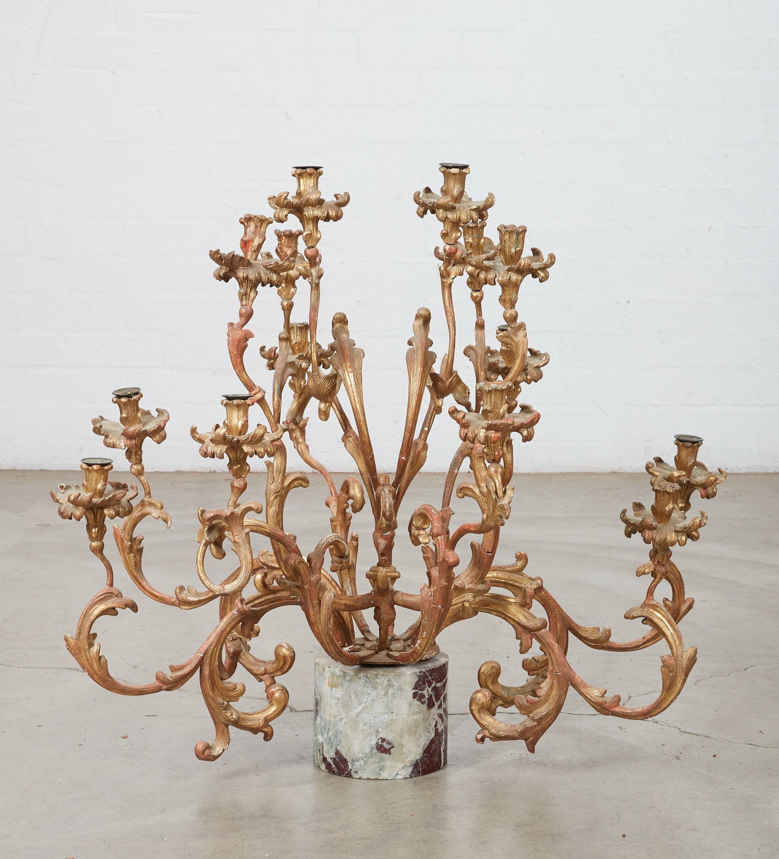 A Rococo style fourteen light candelabrum: A Rococo style carved giltwood fourteen light candelabrum incorporating antique and later elements On round marble base. height 33in (82.5cm); diameter 38 1/2in (96cm)
