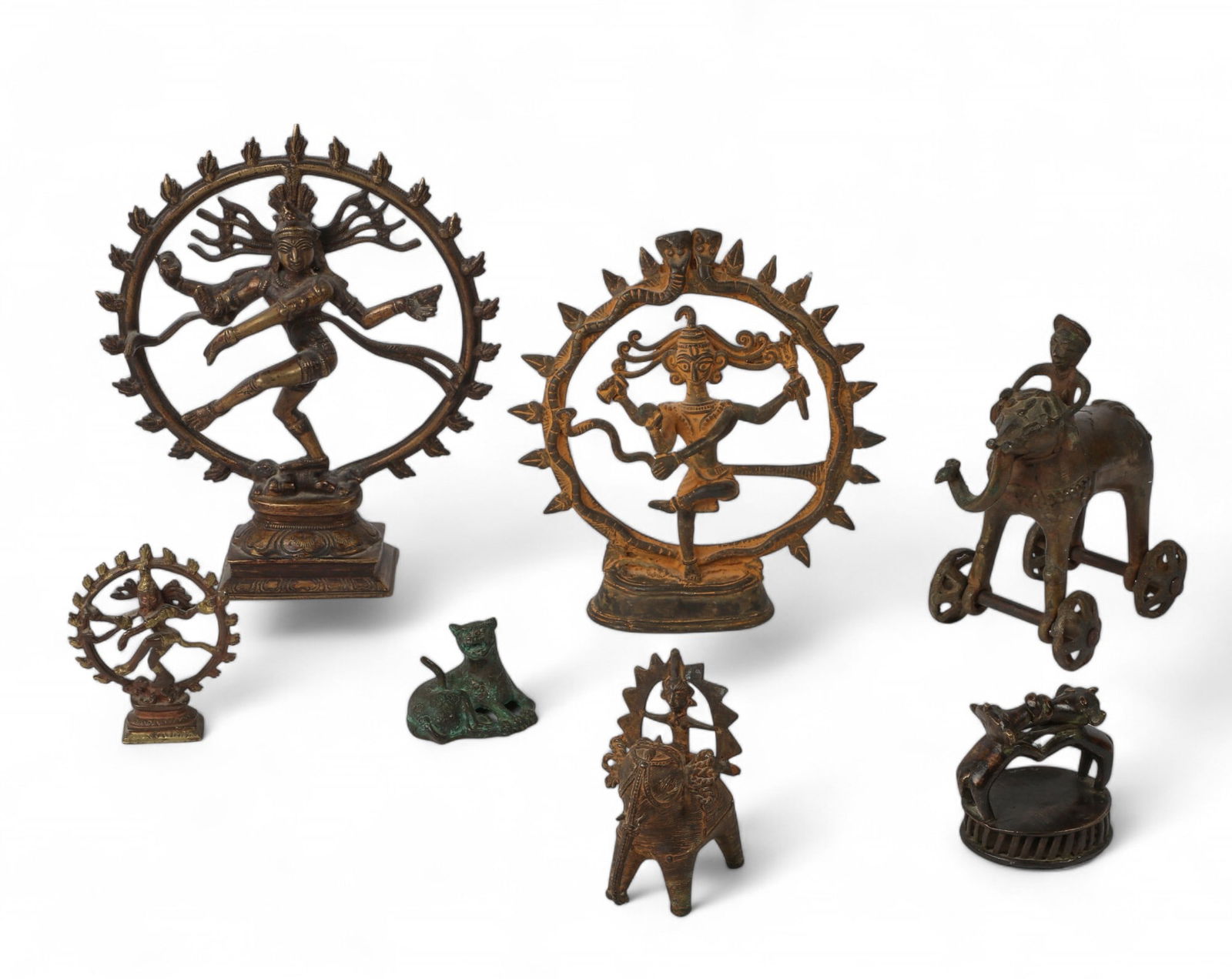 Seven Asian metal table decorations: Seven Asian metal table decorationsComprising three Shiva Nataraja, a bronze figural vajris (foot scrubber), a bronze pull toy modeled as an elephant and rider, and two others.heights ranging from 2in