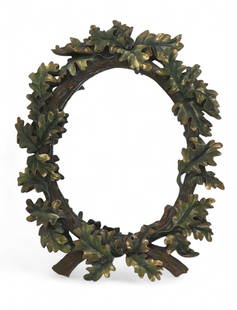 An oval mirror with carved and polychrome-painted oak leaf wood frame: An oval mirror with carved and polychrome-painted oak leaf wood frameThe frame carved in relief with overlapping oak leaves and intertwined branches, painted in green and bronze-gilt tones.height 27in