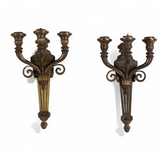 A pair of gilt bronze three-light wall sconces: A pair of gilt bronze three-light wall sconcesEach with foliate-carved urn issuing three scrolling candle arms with urn-form nozzles, the tapered backplate with acanthus decorationheight 18 x width 10