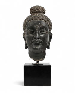 A Southeast Asian Gandharan type schist head of a Bodhisattva: A Southeast Asian Gandharan type schist head of a BodhisattvaDepicted with urna and ushnisha, on later stand, with partial old printed label to underside of stand This is the property of Thomas J. Plo