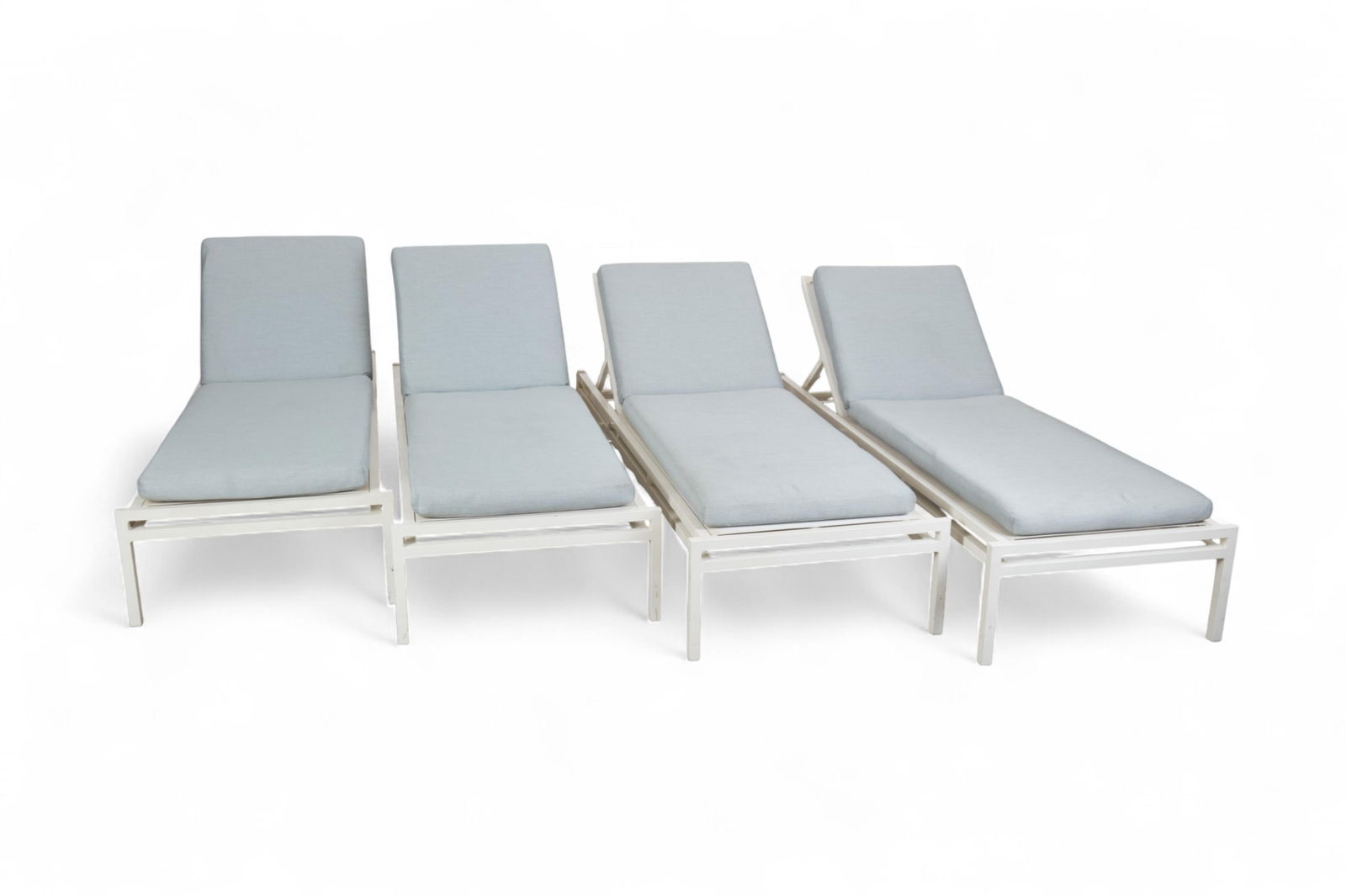 A set of four Janus et Cie white chaise lounges with associated Janus et Cie cushions: A set of four Janus et Cie white chaise lounges with associated Janus et Cie cushionsheight 14 x width 27 x length 79 in. (35.6 x 68.6 x 200.7 cm.)