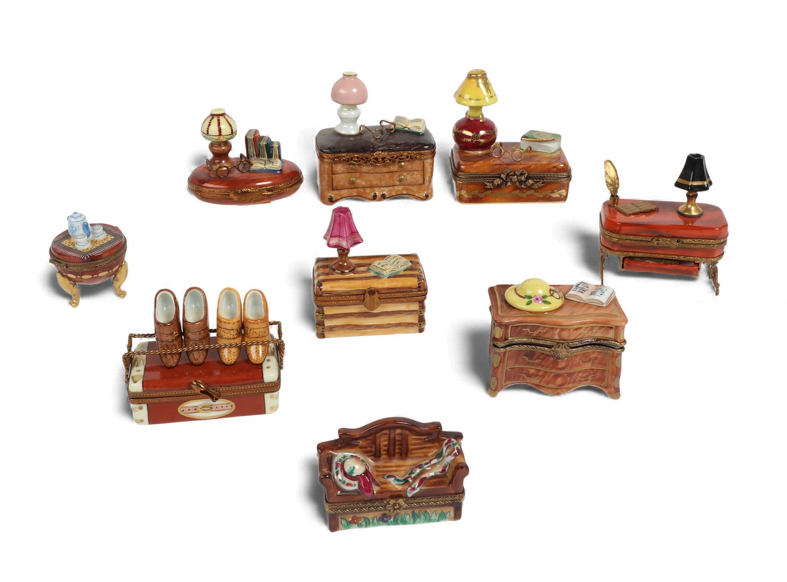 A collection of nine Limoges porcelain trinket boxes modeled as domestic interior furnishings: A collection of nine Limoges porcelain trinket boxes modeled as domestic interior furnishings20th centuryIncluding a model of a shoe rack with two pairs of porcelain shoes, two commodes, and a writing