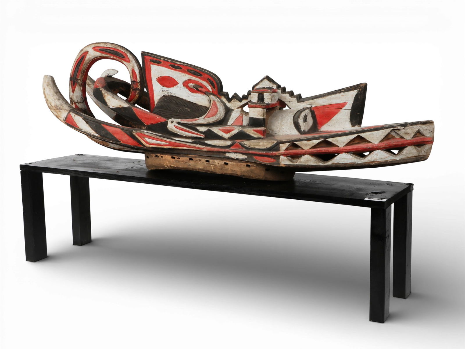 An articulated hand carved and painted mask on black lacquered stand: An articulated hand carved and painted mask on black lacquered stand Mask: height 16 x width 49 x depth 12 in. (40.6 x 124.5 x 30.5 cm.)