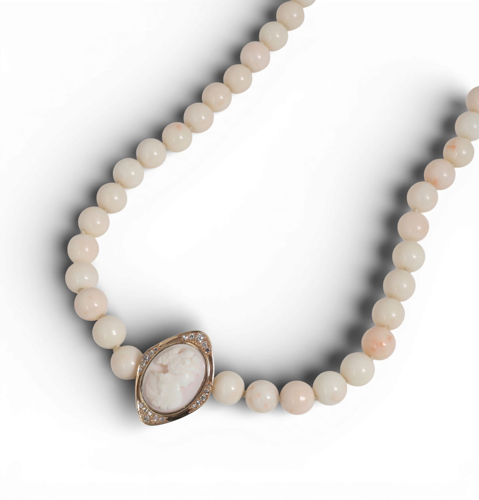 A coral, shell cameo, diamond and 14K yellow gold necklace,length 33in (84cm): A coral, shell cameo, diamond and 14K yellow gold necklaceSingle strand of numerous round white coral beads measuring approximately 10.5 to 11.5mm each, completed by a shortener clasp centering an ova