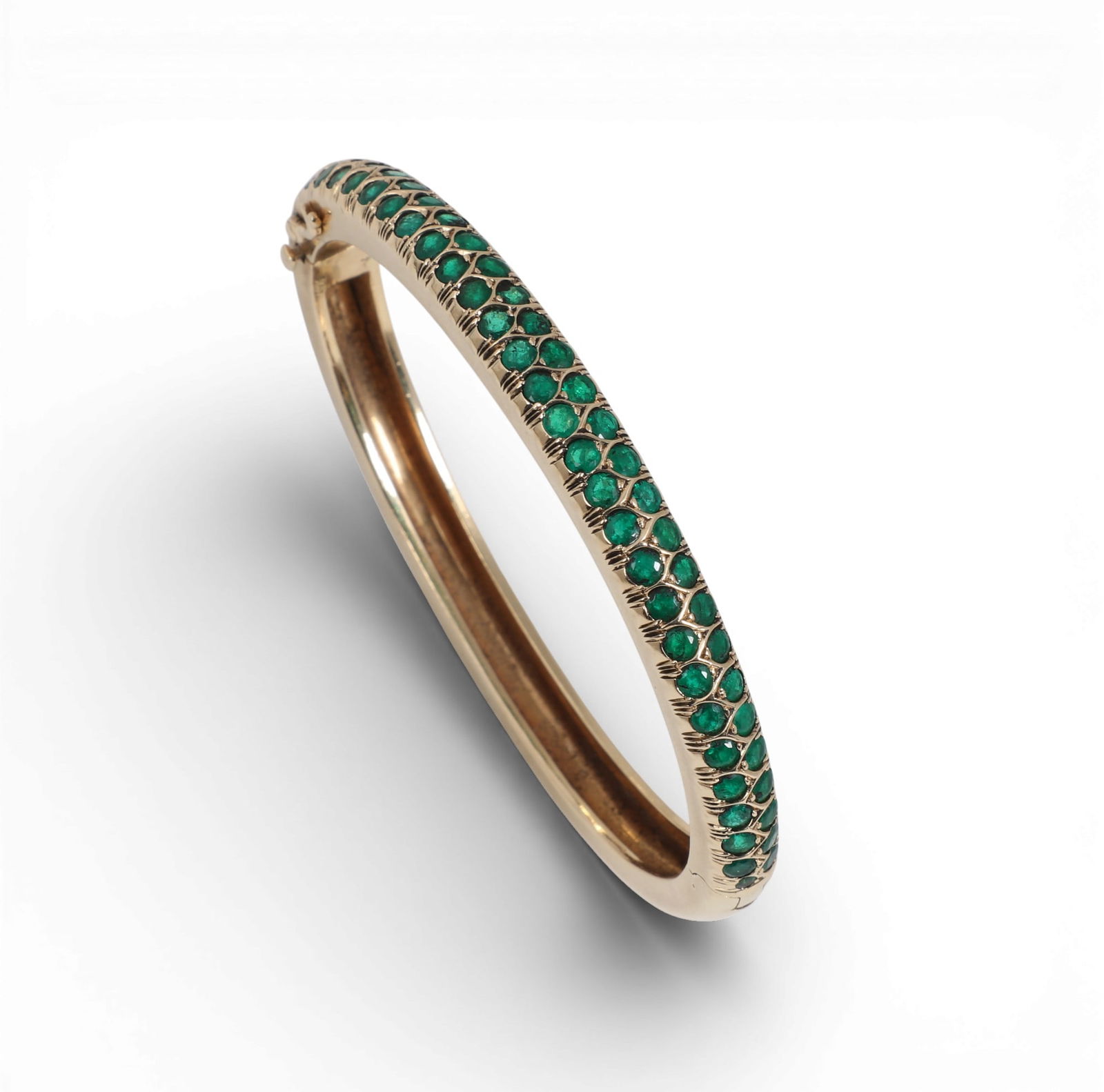 Laykin et Cie: An emerald and 14K yellow gold bangle bracelet,inside diameter measures approximately: Laykin et Cie: An emerald and 14K yellow gold bangle braceletHinged bangle set with round-cut emeralds, estimated to weigh 1.10 carats total weight.inside diameter measures approximately 2.25 x 1.85in
