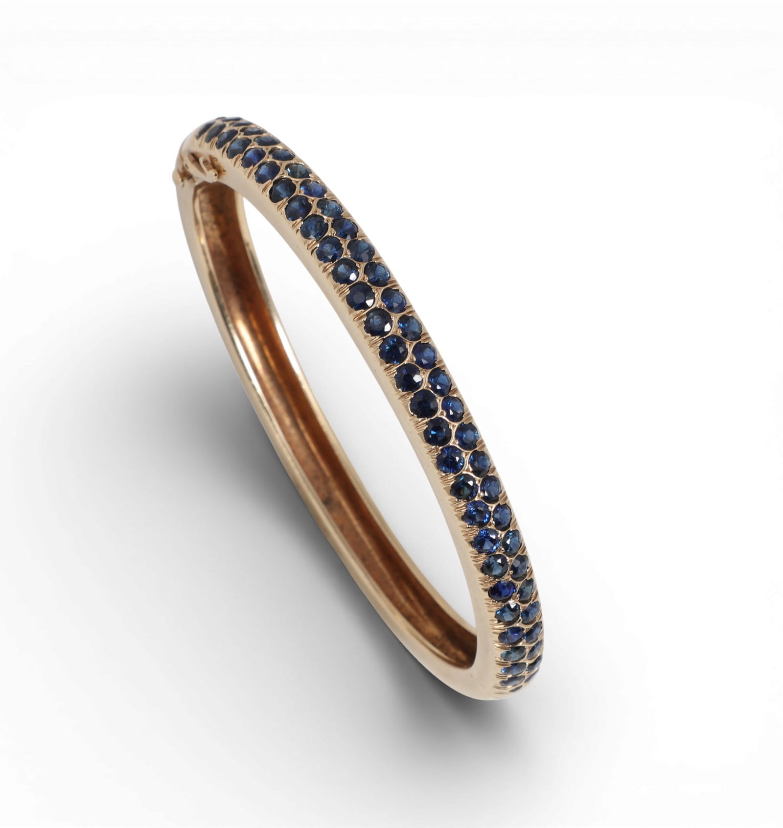 Laykin et Cie: A sapphire and 14K yellow gold bangle bracelet,inside diameter measures approximately: Laykin et Cie: A sapphire and 14K yellow gold bangle braceletHinged bangle set with round-cut sapphires, estimated to weigh 1.20 carats total weight.inside diameter measures approximately 2.25 x 1.85i