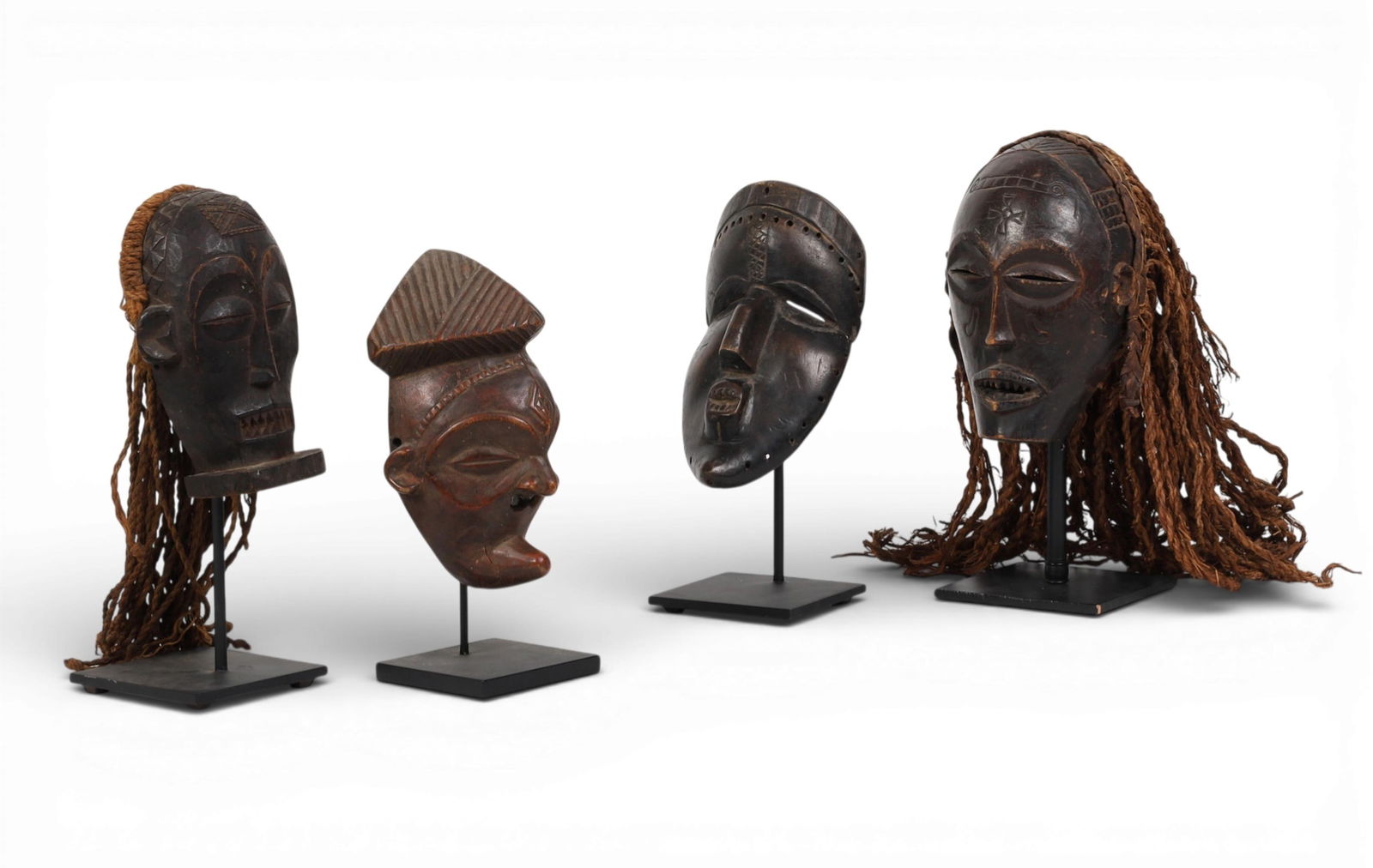 A group of four carved wood African masks on metal stands (1 of 6)