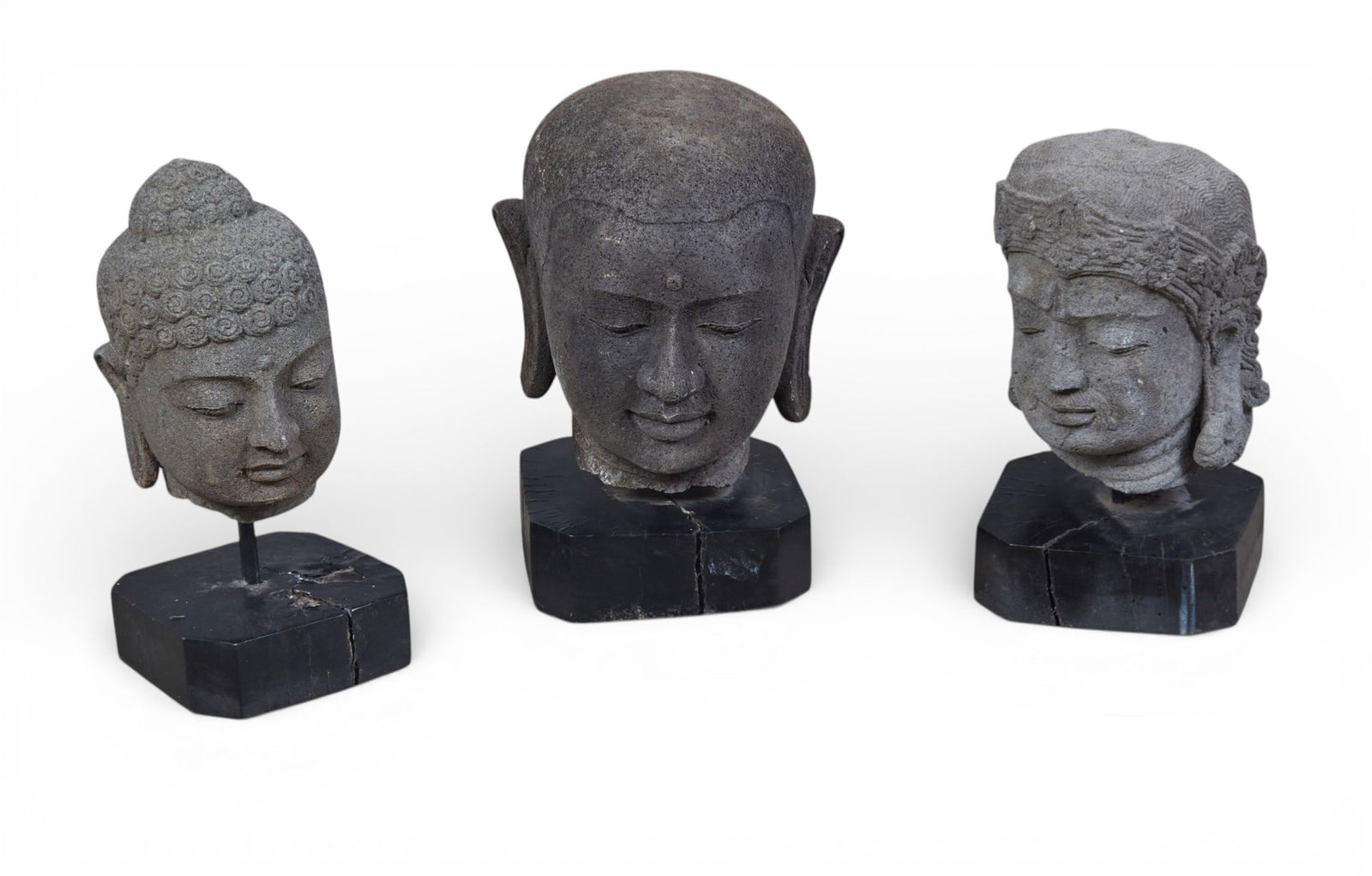 A group of three carved stone buddha heads on stands (1 of 5)
