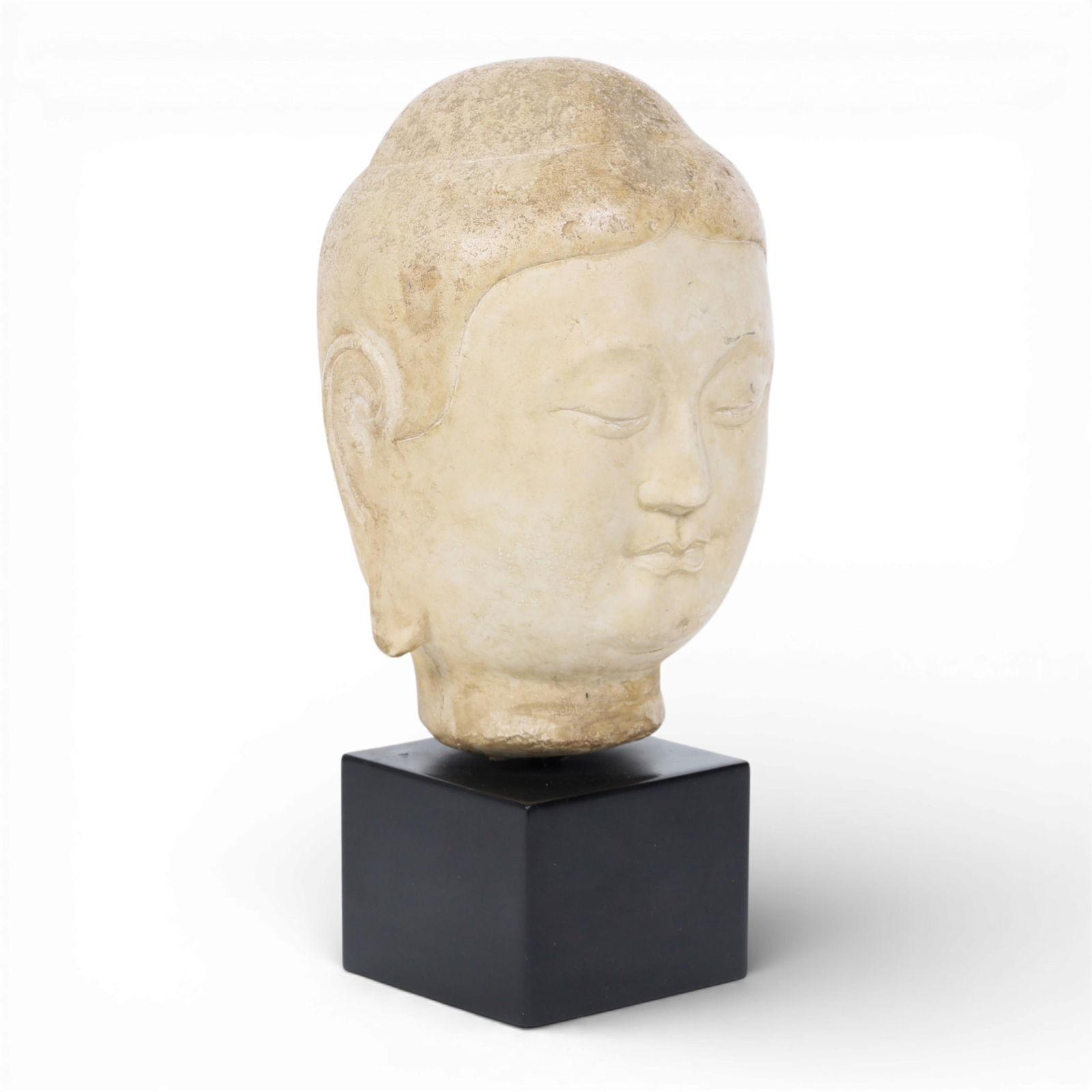 An alabaster head of Buddha: An alabaster head of Buddha head height 10 1/2in (27cm); width 6 1/4in (16cm); depth 6in (15cm); overall height 13 3/4in (35cm)