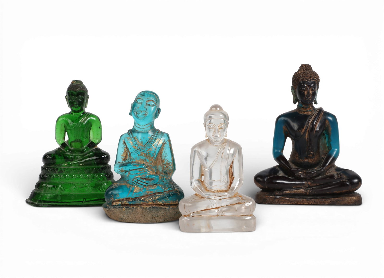 Four Asian quartz, glass and resin seated devotional figures: Four Asian quartz, glass and resin seated devotional figures Three models of Buddha and one of a monk. largest height 6 1/4in (16cm); width 4 3/4in (12cm); depth 2 1/4in (6cm) Provenance: Property