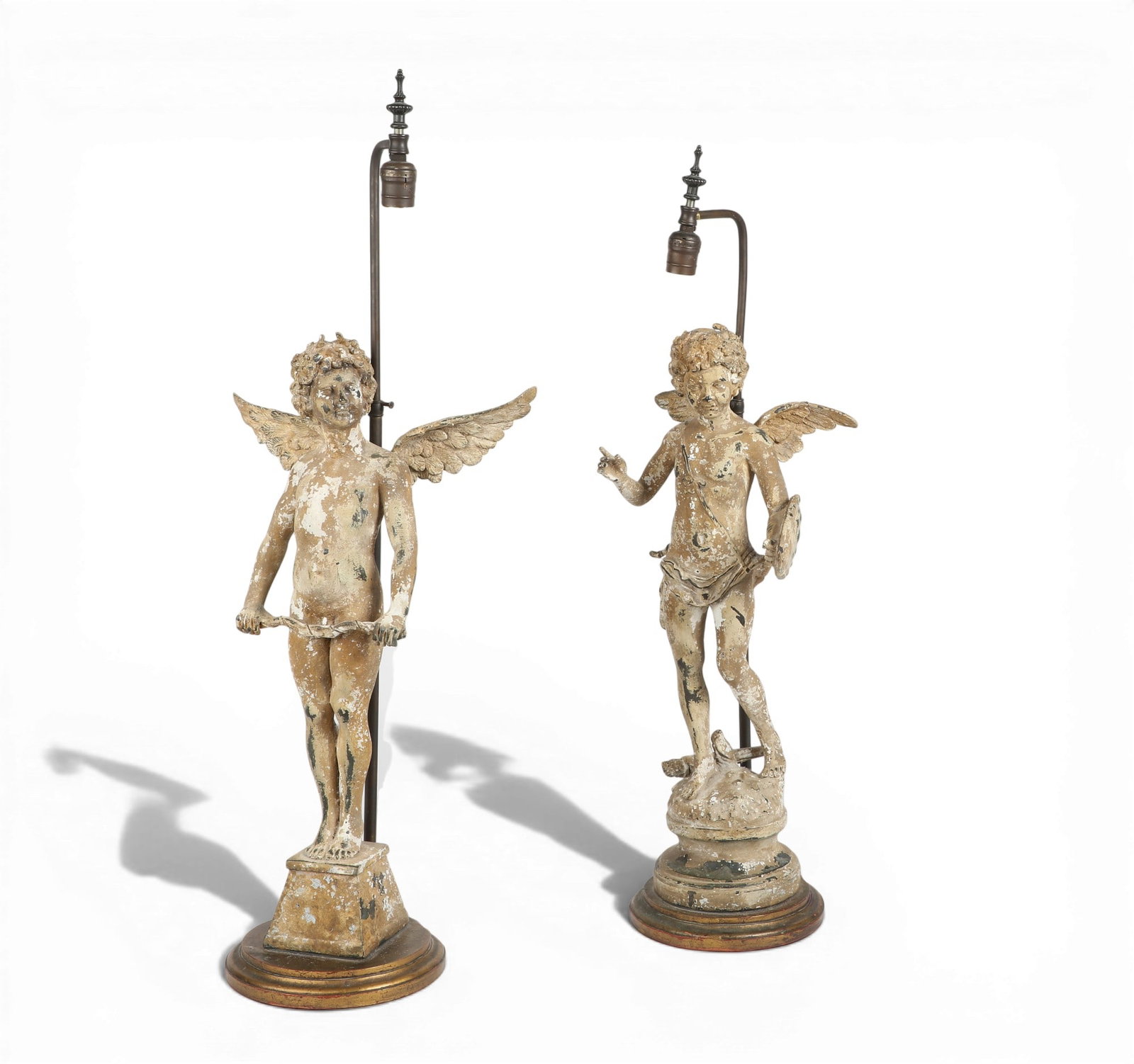 A pair of white painted cast metal putti now as table lamps, 20th century: A pair of white painted cast metal putti now as table lamps 20th century figures height 24in (61cm); width 13in (33cm); depth 7in (18cm)