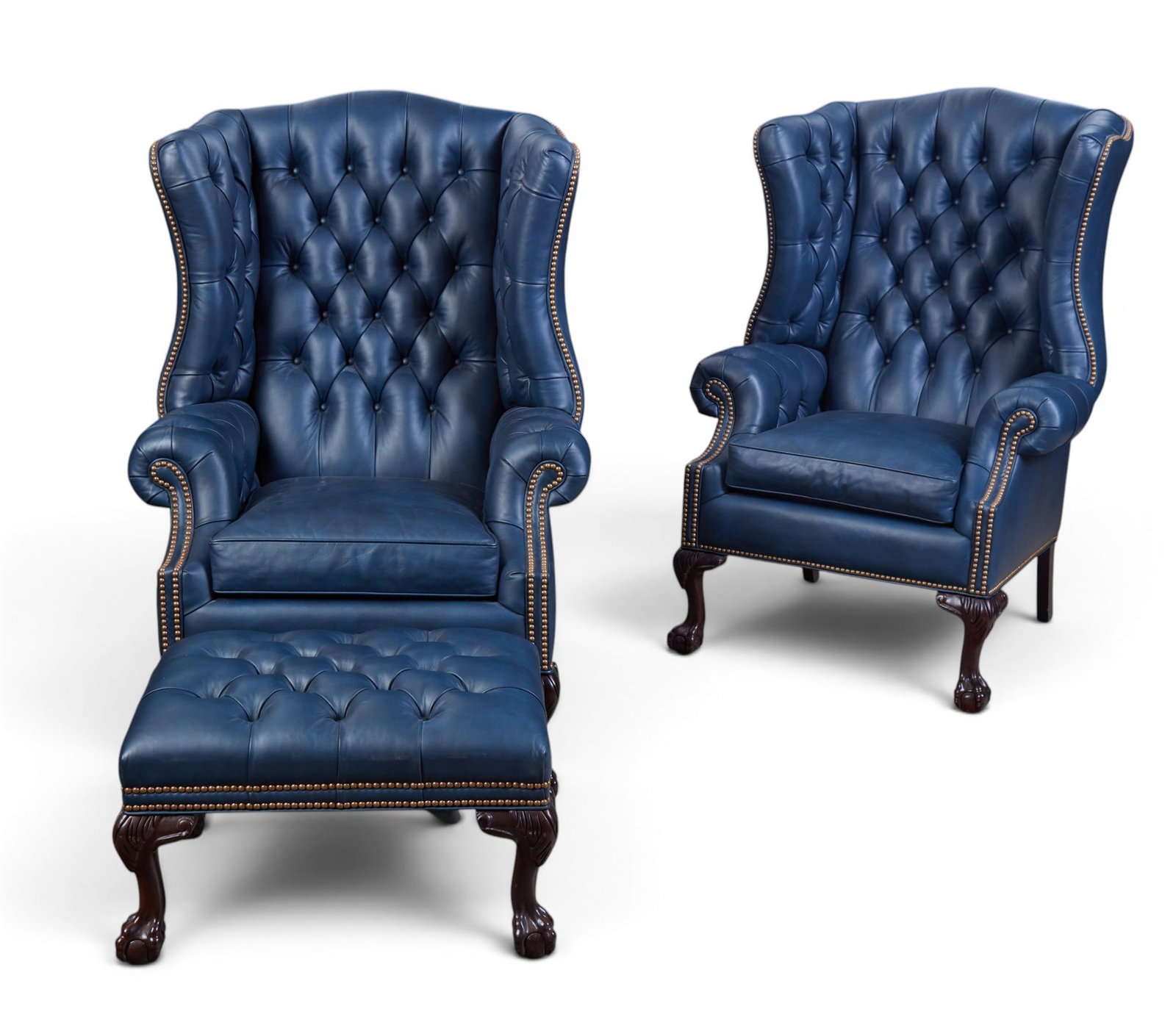 A pair of Hancock & Moore George II style blue tufted leather wing armchairs and matching ottoman: A pair of Hancock & Moore George II style blue tufted leather wing armchairs and matching ottoman modern With maker’s labels. chairs height 51in (130cm); width 34 1/2in (88cm); depth 21in (53cm) Pro