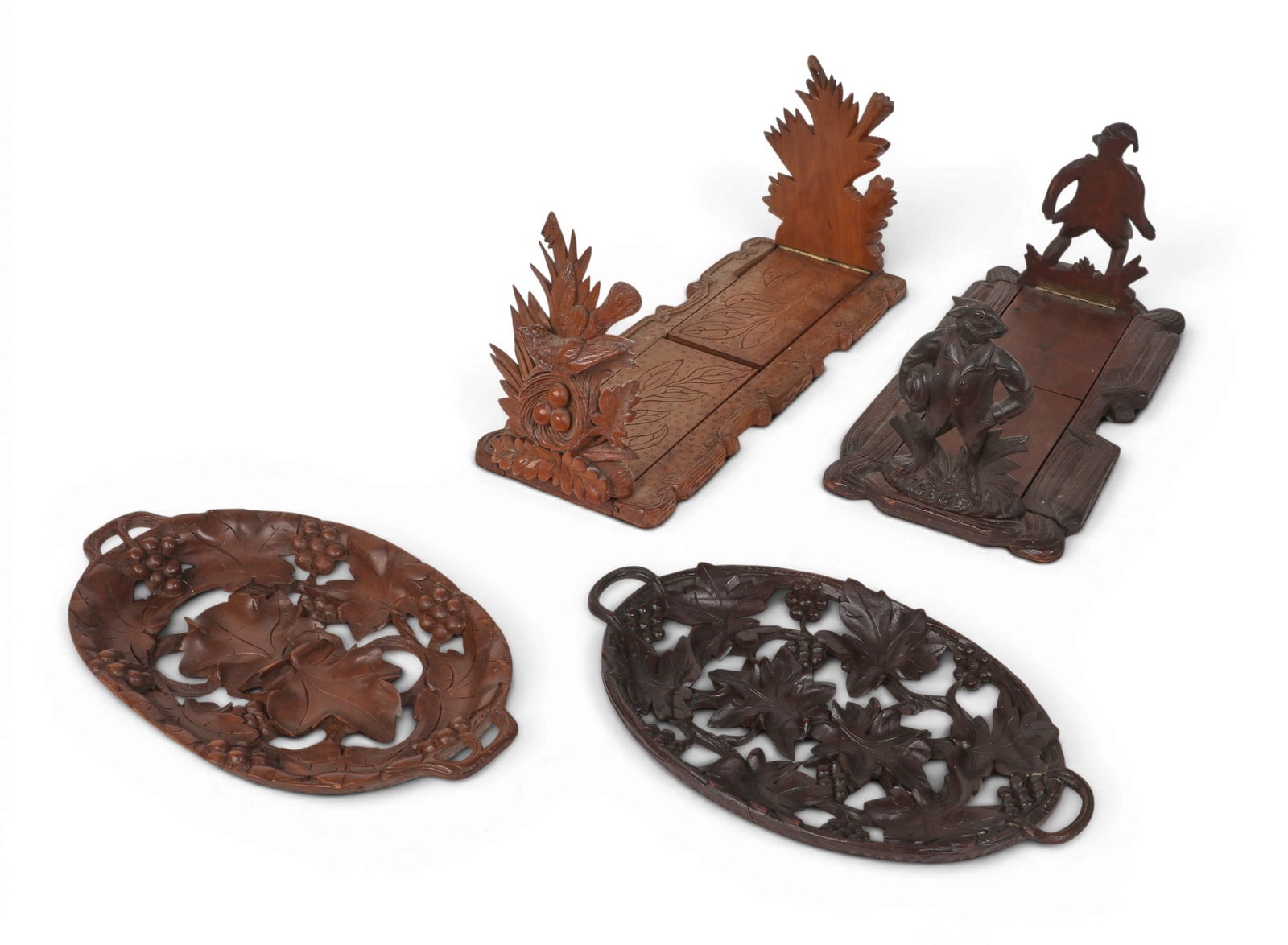 A four piece group of Black Forest carved lindenwood articles, late 19th/20th century: A four piece group of Black Forest carved lindenwood articles late 19th/20th century Comprising two figural sliding book racks, one with anthropomorphic rabbit decoration and the other with a bird and